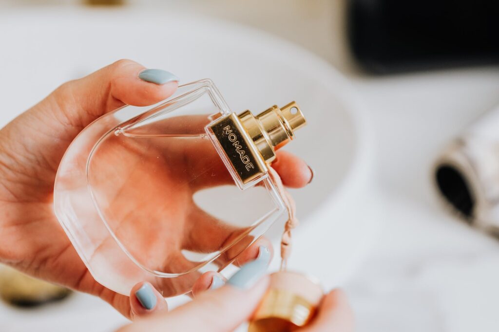 hand holding a clear glass bottle of perfume